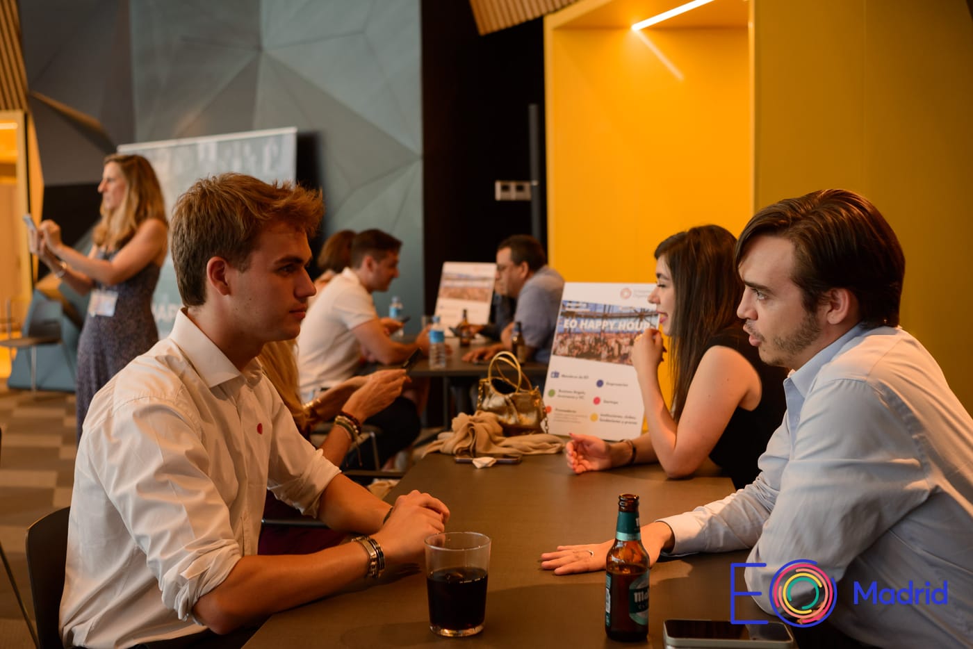 Dos asistentes conversando en una mesa durante el EO Happy Hour