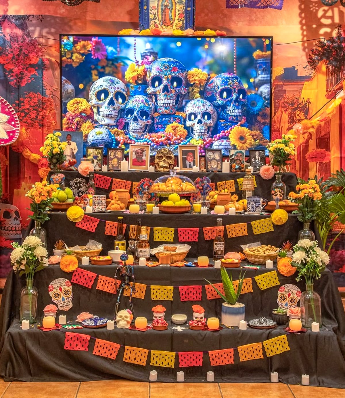 Altar de Día de Muertos de tres gradas con papel picado, calaveras de azúcar iluminadas, flores de cempasúchil, retratos familiares, pan de muerto y velas